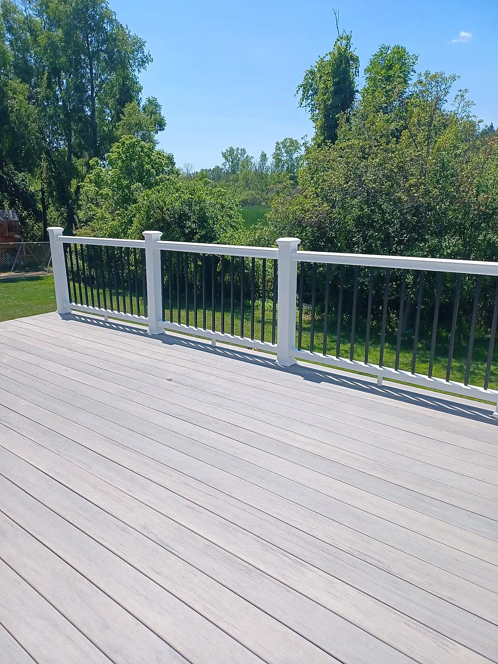 Composite deck with white cable railing under a blue sky
