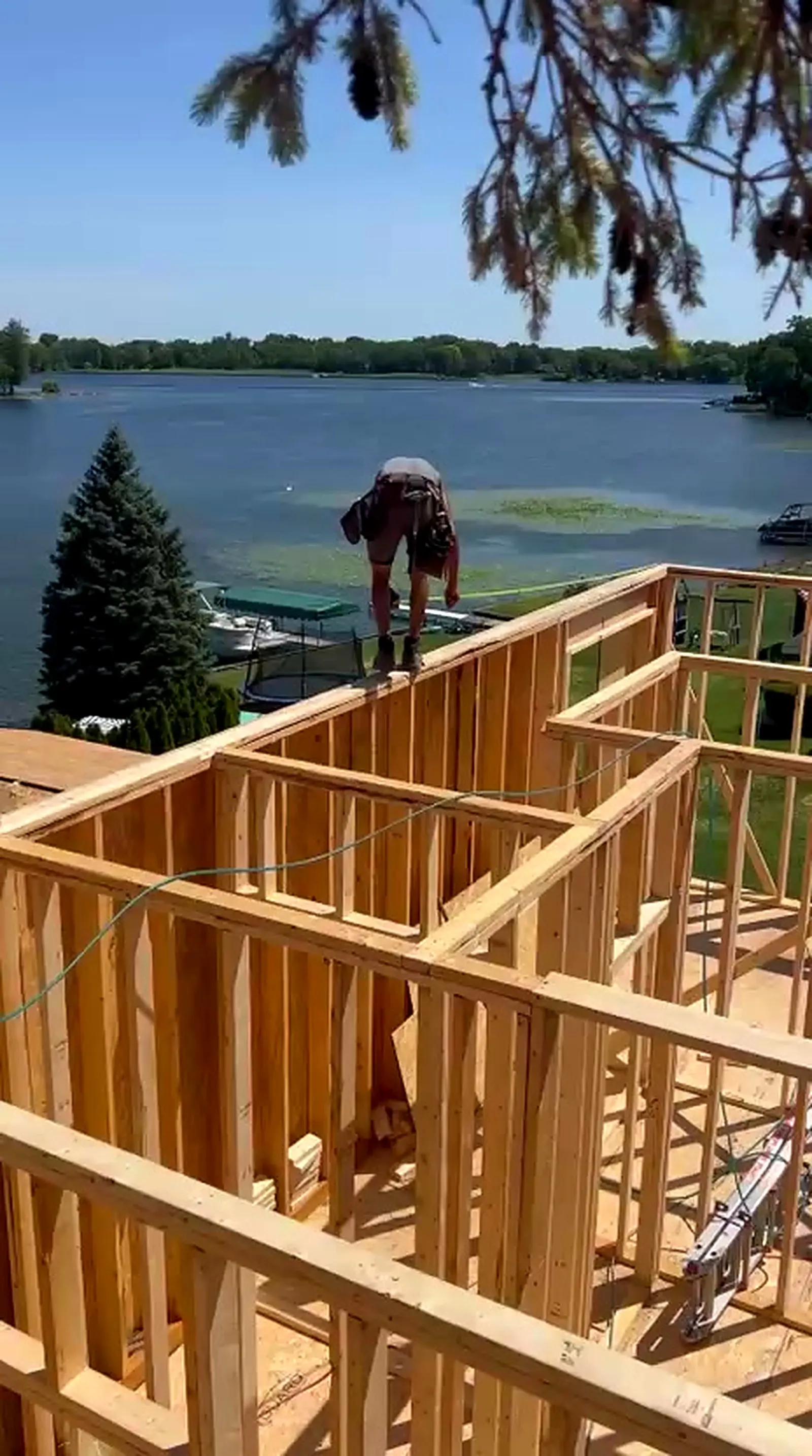Framer on the roof framing of a lakefront home with open water behind, White Lake MI