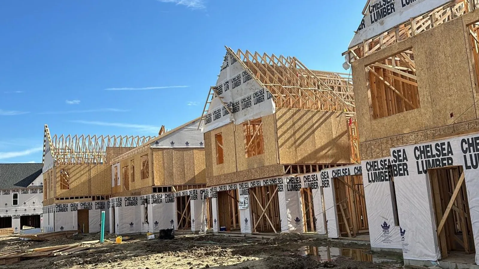 Large multi-unit residential building in rough framing stage, wall and roof framing by Mavericks Construction