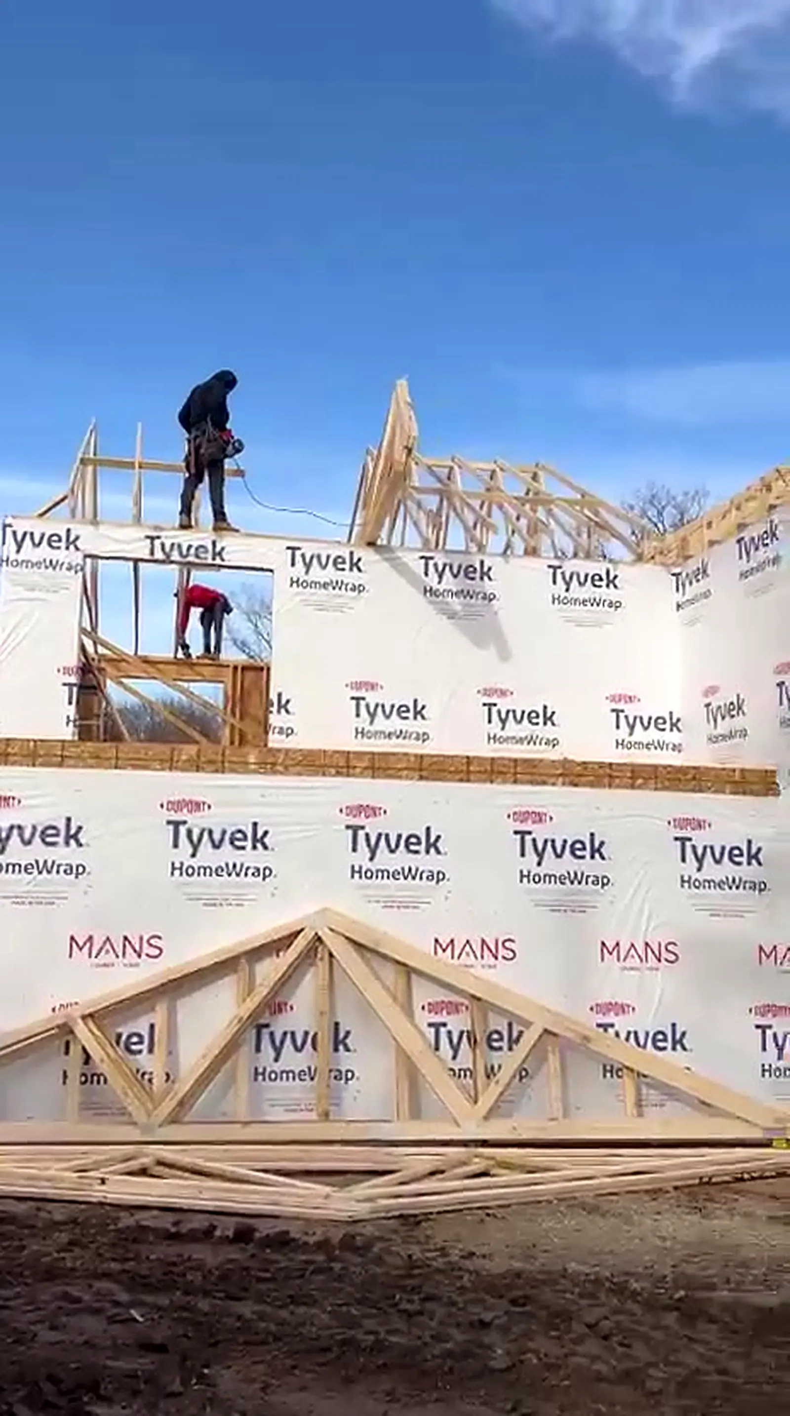 Crew setting roof trusses on a house wrapped two story home, Novi MI